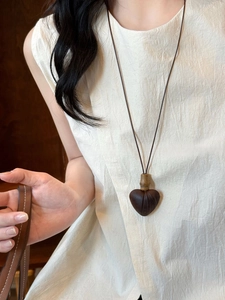 Detail showing heart shaped wood pendant necklace with organic texture on model