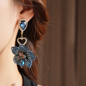 Détail d'une boucle d'oreille fleur en tissu bleu avec strass portée par un mannequin