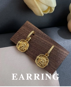 Macro detail of French vintage matte sunburst earrings on dark walnut wood
