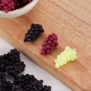 Realistic TPR grape stress toy in purple and green colors on a wooden board