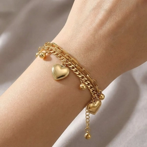Close-up of golden double-layer bracelet featuring heart pendants and small metal beads