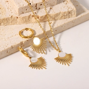 Golden sunflower necklace and earrings set with white shell inlay on stone background