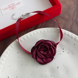 Close-up of burgundy fabric rose choker featuring satin ribbons and adjustable metal clasp