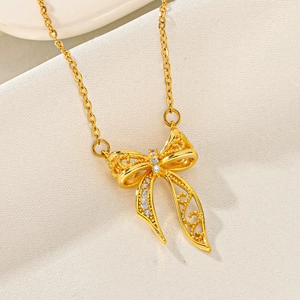Close-up of golden bow pendant with hollow brushed texture and sparkling zircon stones