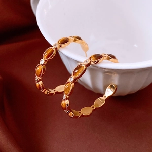Détail de boucles d'oreilles C plaquées or 18 carats avec œil de tigre et zircons