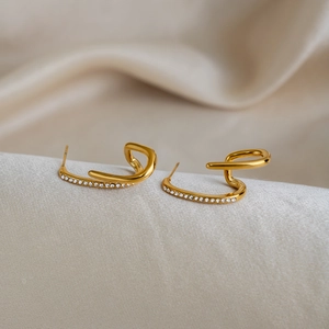 Irregular linear gold earrings with sparkling diamonds on silk champagne fabric
