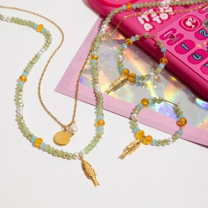 Detail view of colorful glass beads and golden fish charms on necklace and earrings set