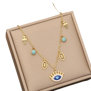 Golden necklace with crown evil eye, Hamsa hand and turquoise pendants in jewelry box