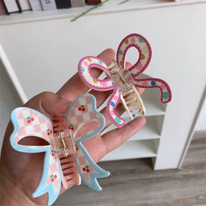 Detailed view of butterfly hair claws with checkered cherry and colorful dot patterns