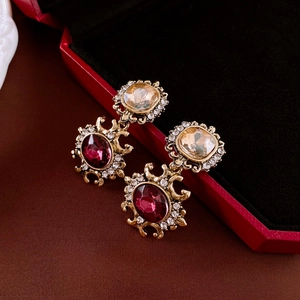 Macro shot of vintage gold earrings with champagne and burgundy stones in a red velvet box
