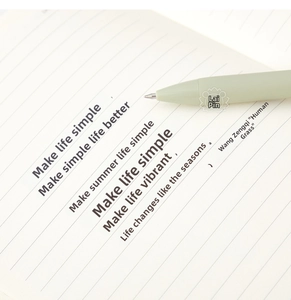 Close-up of matte grey-green gel pen writing smoothly on a lined A6 notebook page
