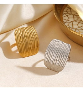 Detailed view of gold and silver rectangle rings with vertical wave textures on silk