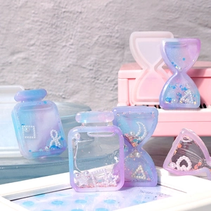 Close-up of DIY resin hourglass and perfume bottle pendants with blue purple glitter