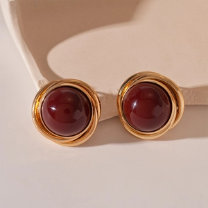Gros plan de boucles d'oreilles vintage en perles rouges et métal doré sur pierre