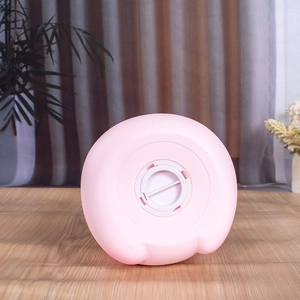 Détail montrant le bouchon d'ouverture blanc sous la tirelire cochon rose mate