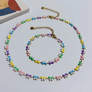 Detail of 18k gold butterfly necklace and bracelet set with colorful enamel charms