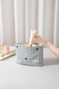 Macro di una mano che ripone prodotti in una borsa per cosmetici a scacchi in bianco e nero