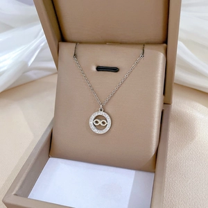 Macro shot of silver titanium infinity pendant with small diamonds in a brown jewelry box