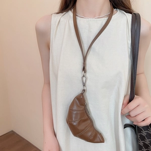 Détail du mini sac croissant en cuir PU marron porté par un mannequin en haut crème
