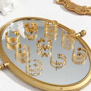 Detailed set of gold open stainless steel rings with floral, leaf, and love designs on tray