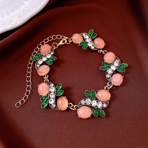 Detailed top view of vintage-style bracelet with pink gems and green leaves on silk