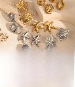 Macro shot of stainless steel starfish and floral earrings with gold vacuum plating finish