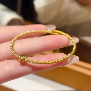 Detail of 24K gold-plated beaded bracelet with matte faceted beads and spiral central bead