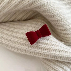 Vue détaillée d'une pince à cheveux nœud en velours rouge foncé sur un tissu en maille blanc