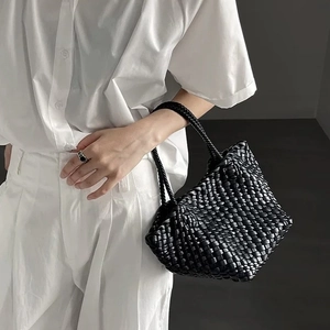 Detail of premium black hand-woven leather handbag showcasing intricate weaving texture