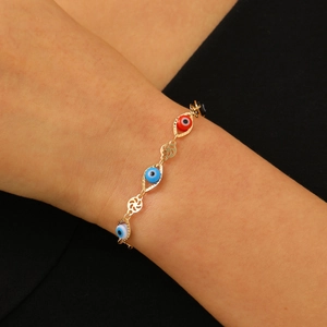 Gros plan d'un bracelet chaîne doré avec perles œil grec colorées sur poignet femme