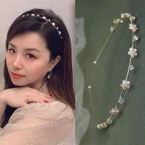 Dettaglio di un sottile cerchietto dorato con fiori rosa e strass luccicanti