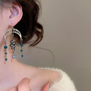 Close-up of silver snake and moon earrings with tassels on a model for a boho look