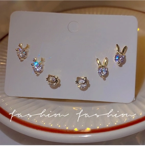 Macro detail of gold-plated animal stud earrings with shimmering white zircon stones