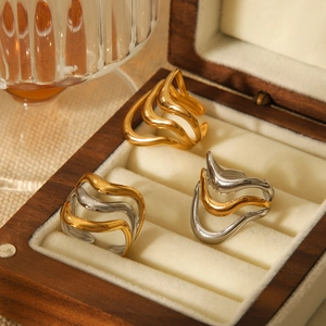 Detailed view of wavy stainless steel rings in gold and silver finish in a jewelry box