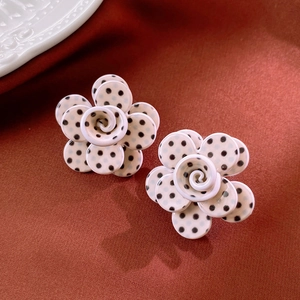 Macro shot of 3D layered polka dot flower earrings on elegant silk background