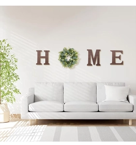 Rustic wood HOME letters with faux plant wreath mounted above a white living room sofa