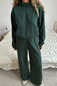 Detailed view of dark green half-zip sweatshirt with harmony embroidery and wide-leg pants