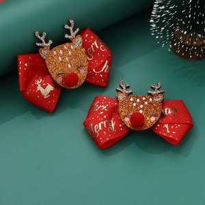 Detail of red Christmas bow hair clips with glitter reindeer and festive gold lettering