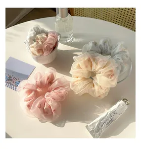 Dettaglio di elastici per capelli in organza con motivi a margherita su tavolo bianco