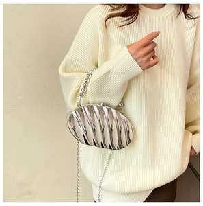 Detail of silver shell-shaped acrylic clutch with metallic bead handle and chain strap