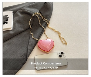 Pink heart-shaped mini clutch with gold chain compared to a smartphone for scale