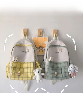 Detail of plaid student backpacks in yellow and green with cute plush bear and rabbit charms