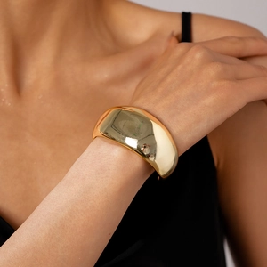 Polished gold minimalist wide cuff bracelet showing mirror reflection on a model's wrist