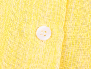 Macro shot of yellow linen fabric texture with a white four-hole button detail
