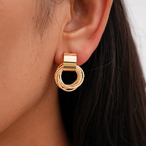 Detail of a model wearing a gold geometric rectangular earring with intertwined textured rings