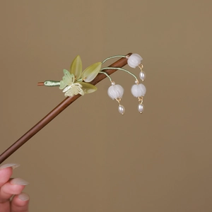 Detail of wooden hair pin with green leaves, white lily of the valley and pearl tassels