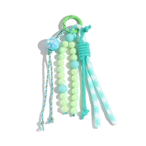 Détail d'un porte-clés à perles vertes avec boule marbrée et pompon tressé