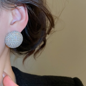 Gros plan de boucles d'oreilles rondes en pavé de zircone portées par un mannequin