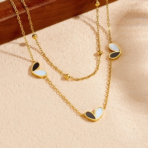 Detail of double-layer gold necklace with black and white heart enamel pendant
