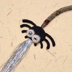 Macro detail of cat teaser wand spider toy with silver tassels and mesh bead string